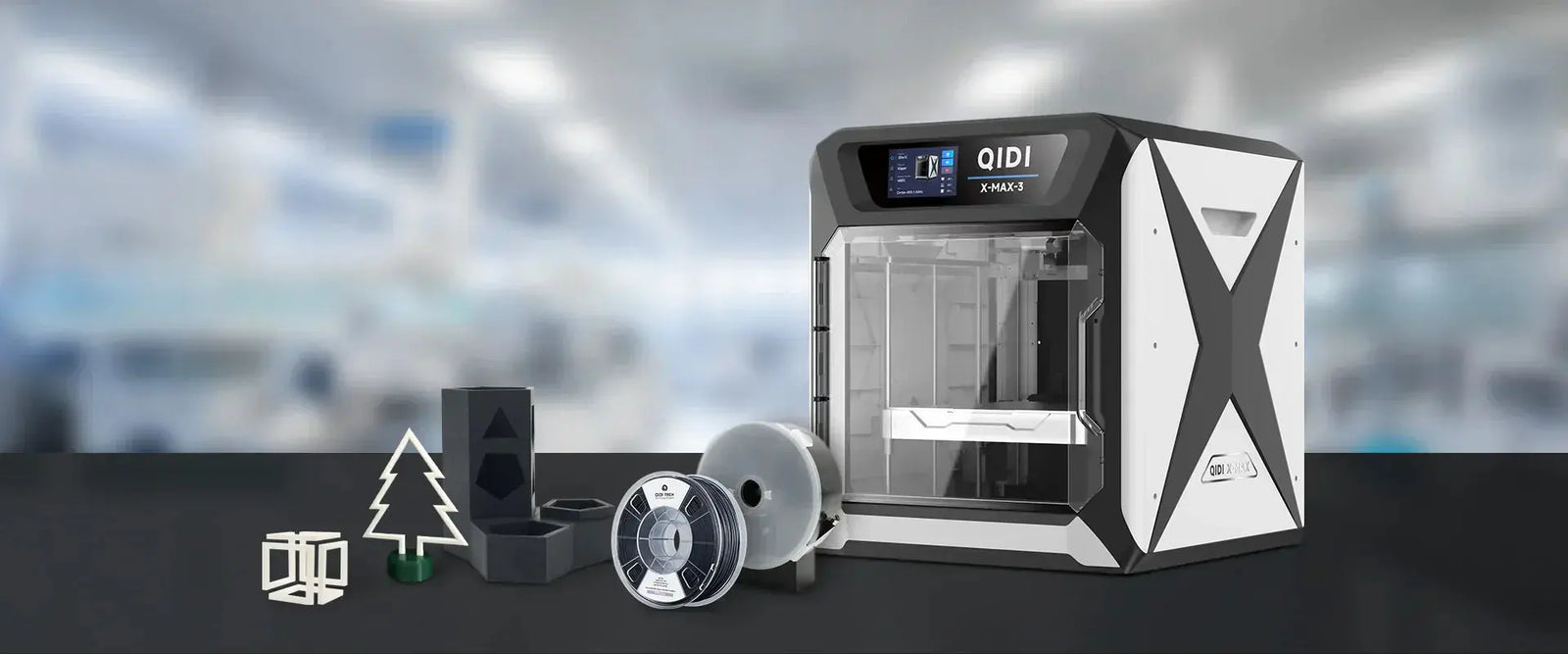 Next to QIDI's X-Max 3 model 3D printer are 3D printing filament reels, some 3D printed finished models, etc.