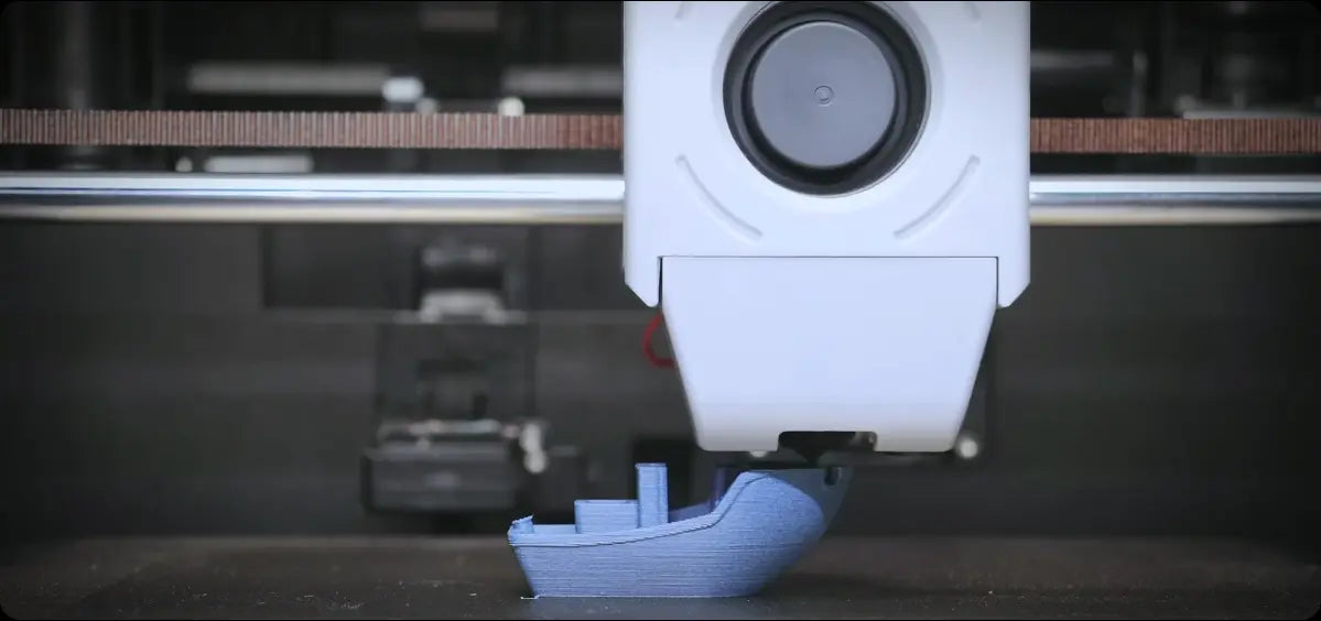 The 3D printer is printing a blue boat model
